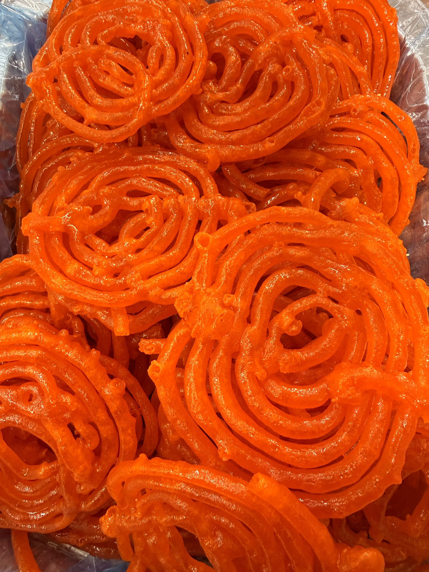 Fresh orange jalebi sweets on the counter at Swadesh Supermarket, Saskatoon